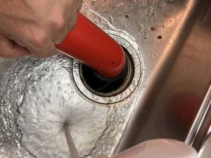 キッチン排水口のつまりを専用ポンプで除去している作業